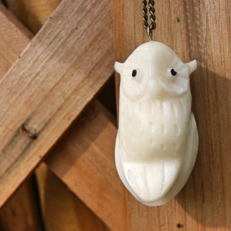 fair trade tagua nut owl necklace hanging on wood