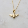 gold plated bee necklace on white marble